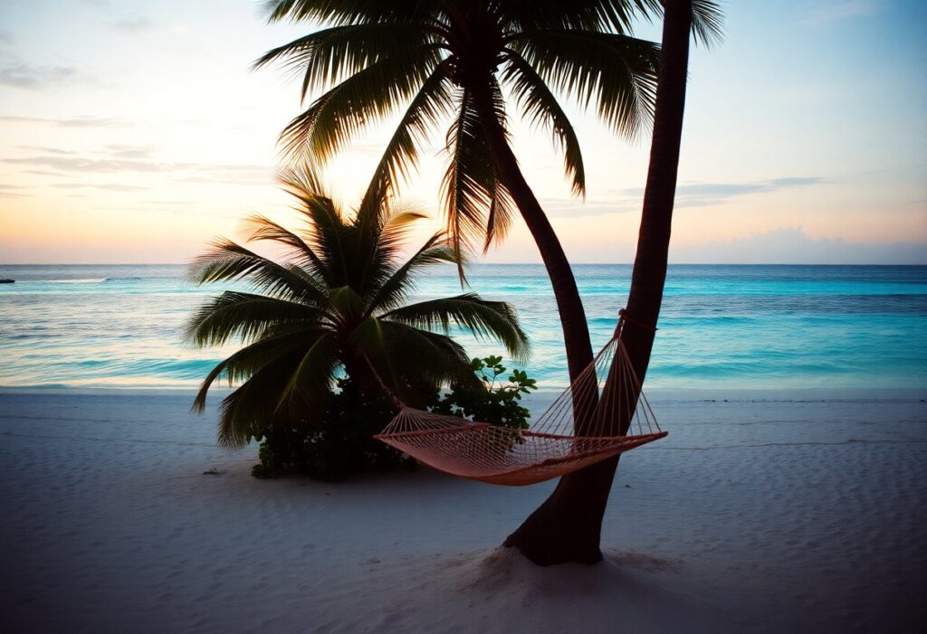 A serene Belize beach scene at sunset features two palm trees, one cradling a hammock. The calm ocean with gentle waves invites relaxation, while the sky’s soft pastel colors rejuvenate the spirit. The sandy shore remains smooth and undisturbed, a perfect haven for peace.