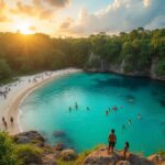 People swim and relax along a crescent-shaped beach with turquoise water, surrounded by dense forest and cliffs, as the sun sets. A Belize travel guide could help you explore hidden spots like this, where two people stand on a rocky outcrop overlooking the scene.
