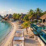 Experience Coco Belize Resort in 2025—luxury beachfront stays with thatched-roof villas over water, private pools, palm trees, and turquoise ocean views all under a sunny sky.
