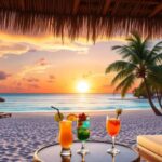 A tropical beach at sunset with palm trees, lounge chairs, and three colorful cocktails on a round table under a thatched roof—experience this paradise with exclusive Belize vacation packages or unbeatable Belize deals.