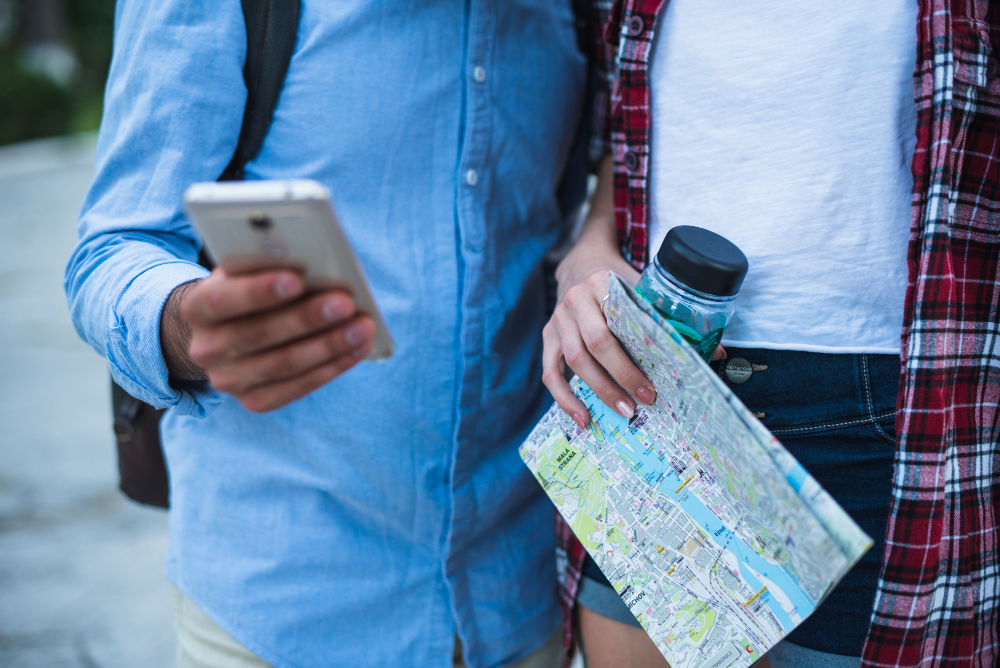 Two travelers consulting a map and a smartphone for navigation.
