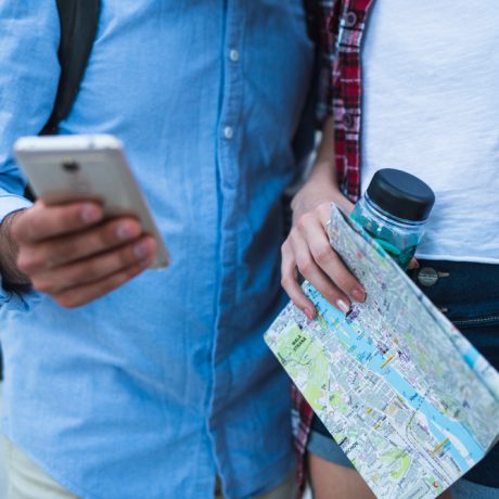 Two travelers consulting a map and a smartphone for navigation.